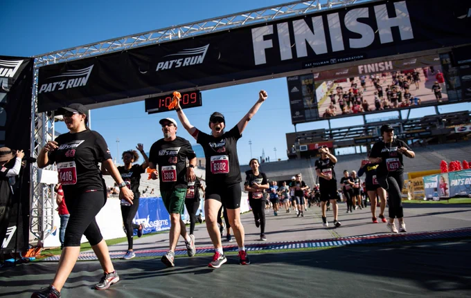 Runners crossing the finish line at Pat's Run, celebrating their completion under a clear blue sky.