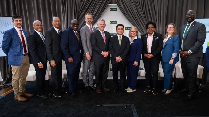 A group of Charlotte and state officials stand in a row on a stage.