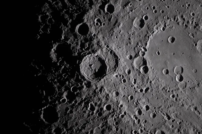 A close view of the Moon. Jagged circles of craters dot the gray surface, fading to dark on the left side of the image. Credit: NASA