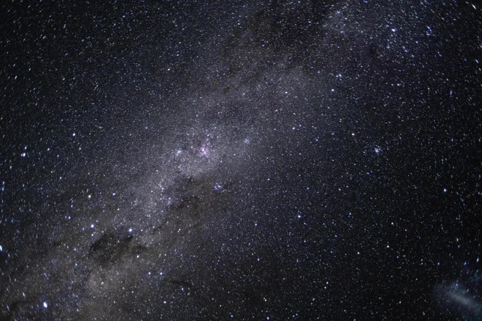 A starfield filled with thousands of stars and shining clouds of dust. The Milky Way\u2019s elegant spiral structure is dominated by just two arms wrapping off the ends of a central bar of stars. Spanning more than 100,000 light-years, Earth is located along one of the galaxy\u2019s spiral arms, about halfway from the center. Credit: NASA