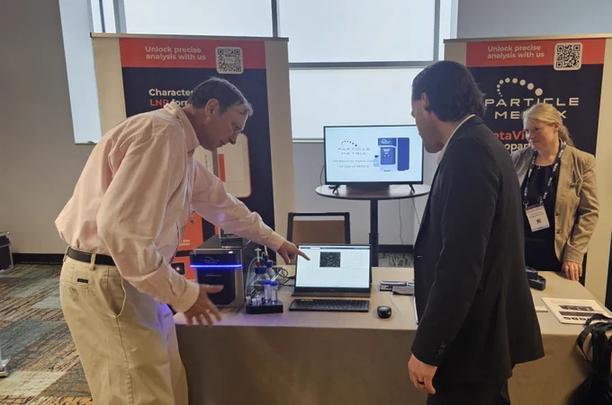 Particle Metrix team engaging with a customer at their booth featuring Zetaview NTA technology.