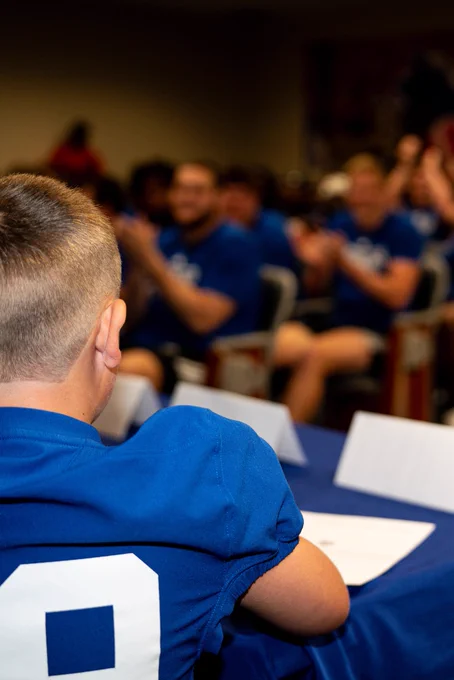 The back of Maddox head looking at a room full of football players