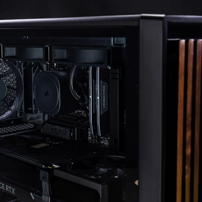 A dynamic image of an all black COrsair build, created in the FRAME Configurator.  The front panel is a dark wood aesthetic that offsets the solid black coloration.   