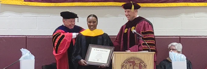 Dr. Murray and President Daly presenting Dr. Lola Brabham Harris with her hood and honorary doctorate
