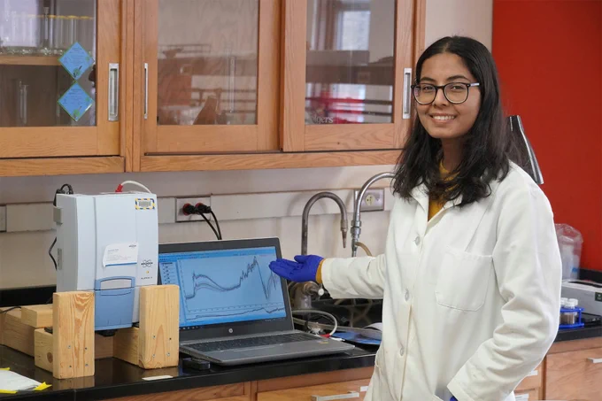 Photo of UW-Madison PhD student Soni Ghimire standing in a lab setting, smiling at the camera.