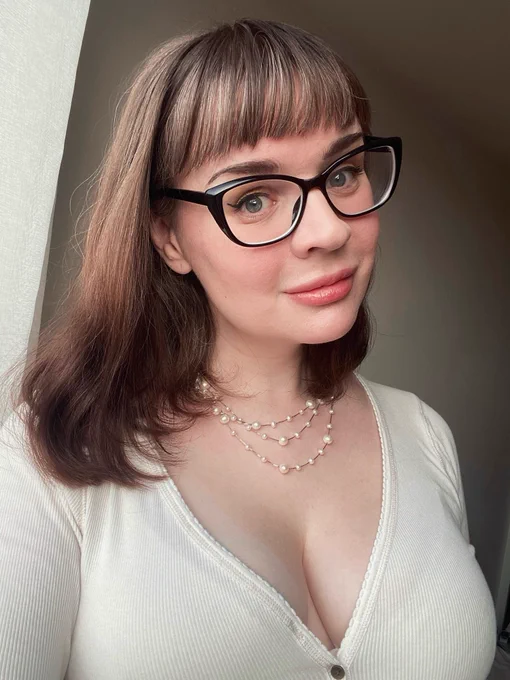Selfie. Three-quarter shot so Avery could include her breasts, which seem full if a little sunburned. That necklace from the second photo is back! Her hair is still long, the bangs less blunt and the brown a lot lighter, with a bunch of greys, too. She’s wearing a cream v-neck/scoop neck button-up long sleeved tee, it’s weird but it looks good. From Abercrombie in 2019, I think.