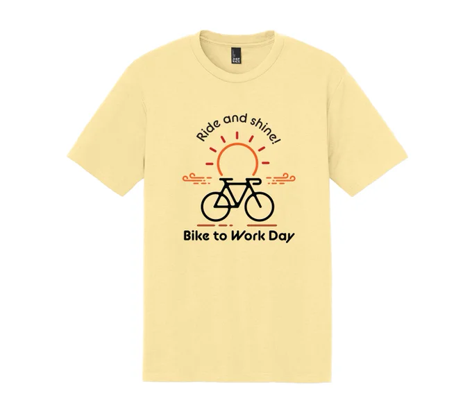 A yellow T-shirt featuring a design of a sun rising behind a bicycle. Text reads "Ride and shine! Bike to Work Day".