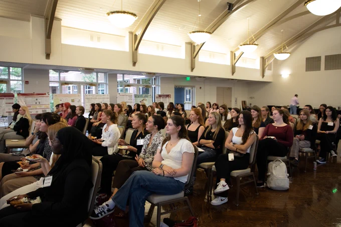 A wide shot of the seated audience during a student's research presentation.