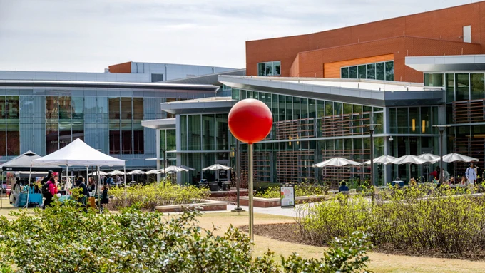 A large red spherical sculpture in the center of Stafford Commons, a grassy courtyard outside of Talley Student Union.
