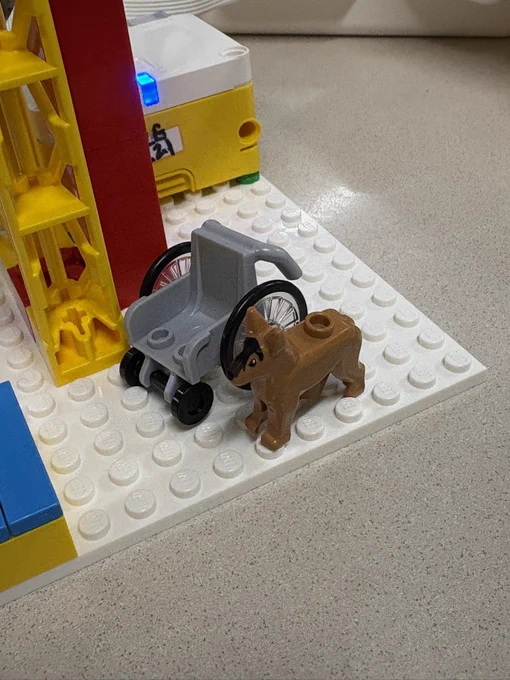 An image of a lego wheelchair and a lego dog standing next to it.