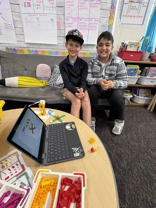 Two boys smiling as the show the Spike lego project they are starting.