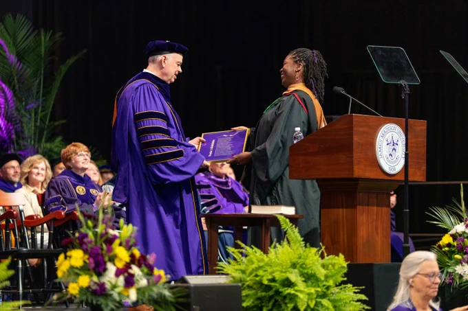 President Jim is presented with a framed copy of “Promise: A (re)definition” a poem by Lauren K Alleyne.