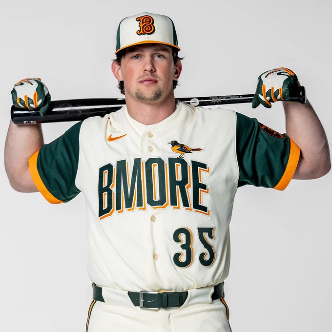 Adley Rutschman posing for a photo in the new Orioles City Connect uniform. He’s holding a bat over his shoulder.