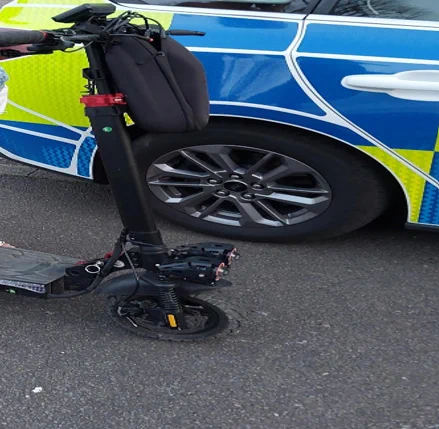 E-Scooter that has been seized by officers parked Infront of a marked police car.