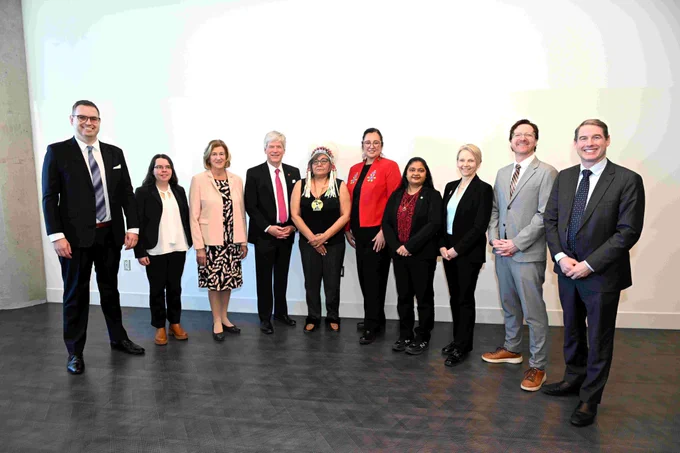 Ten people in business attire posing for a photo.