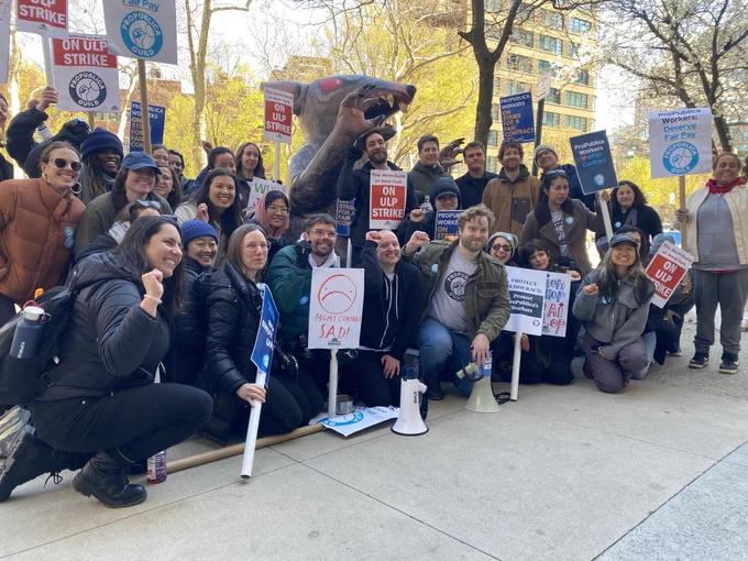 A large group of people holding signs pose for a photo.