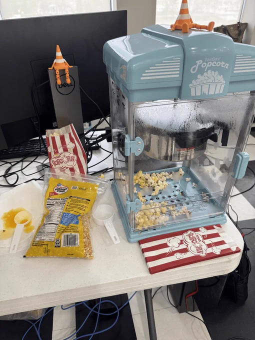 A popcorn machine with a lot of miniature traffic cones (VLCs!) sitting around.