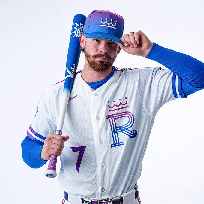 Bobby Witt Jr. posing for a photo. He’s wearing the new Royals City Connect uniform. He’s holding a baseball bat right his right hand and grabbing the brim of his hat with his left hand.