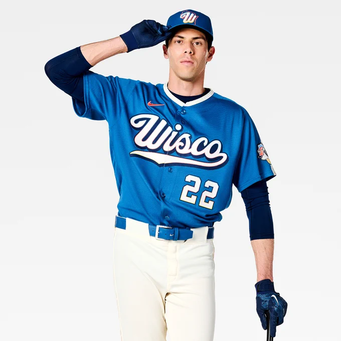 Christian Yelich posing for a photo in the new Brewers City Connect uniform. He’s leaning on a baseball bat and touching the brim of his hat with his right hand.