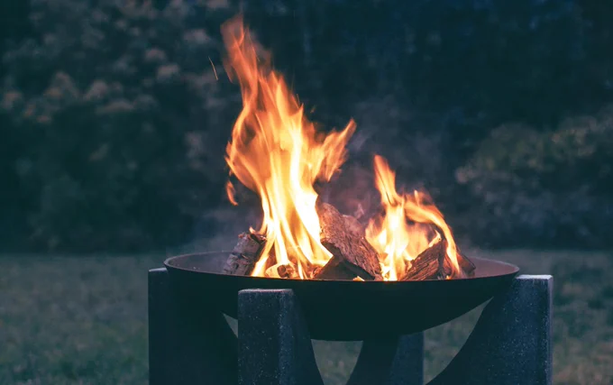 Flames flicker above burning logs in a metal fire pit