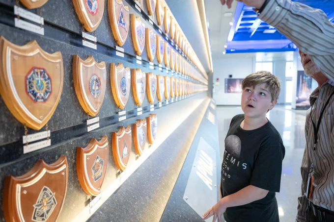 Young boy looking at wall of NASA mission patches