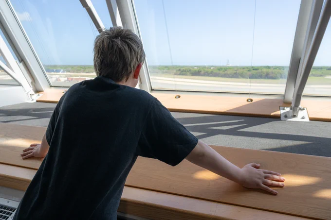 Young boy looking out windows of Launch Control Center