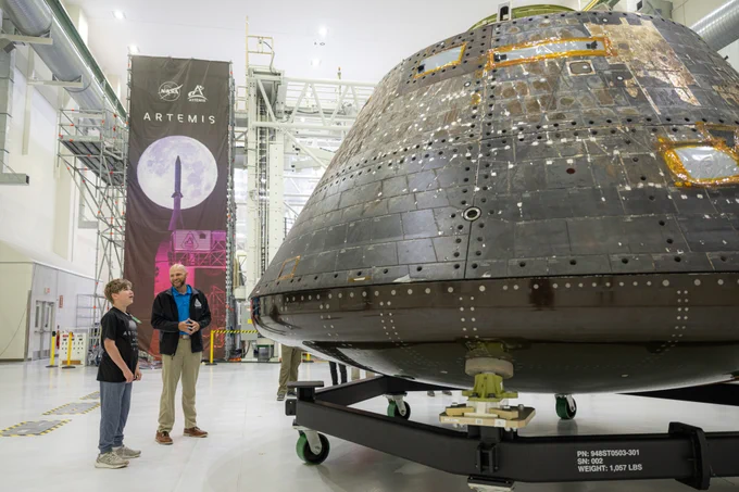 Young boy and man looking at Orion spacecraft