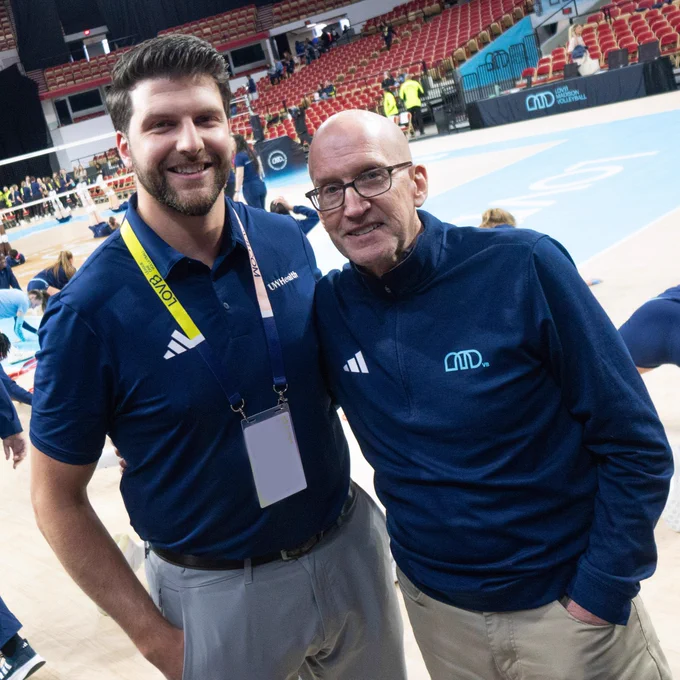 Two people on the sideline of a volleyball court with LOVB med staff credentials. 