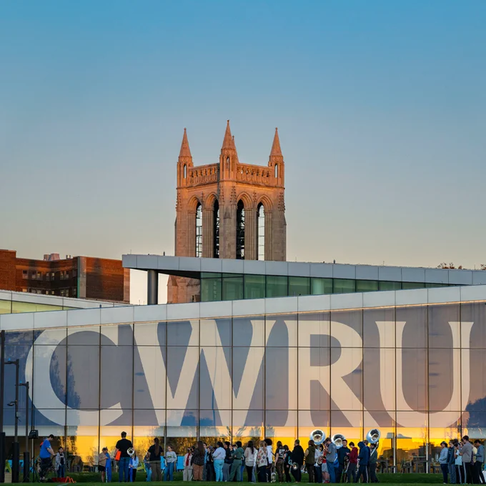 Case Western Reserve University's Tinkham Veale University Center with "CWRU" signage in the foreground, with a group of people gathered in front of the building