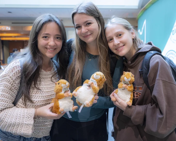Three students holding squirrel plushies 