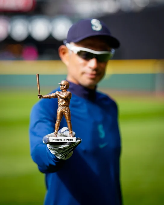 Ichiro Suzuki holds an Ichiro Replica Statue giveaway in his extended right hand