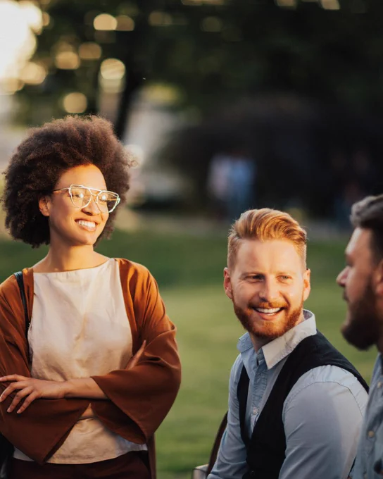 A photo of a man and woman in business attire smiling at another man in their group.