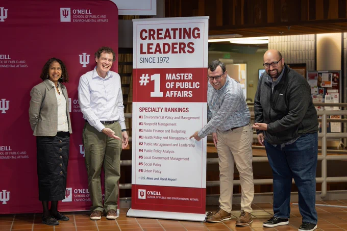 Four O'Neill faculty stand next to a banner that reads "Creating Leaders Since 1972" and highlights a "#1 Master of Public Affairs" ranking from U.S. News & World Report. They are pointing at the speciality ranking for #1 Health Policy and Management.