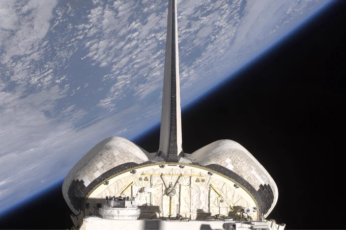 A photo featuring the view from the back of a spacecraft. Behind it is the curved horizon of the earth.