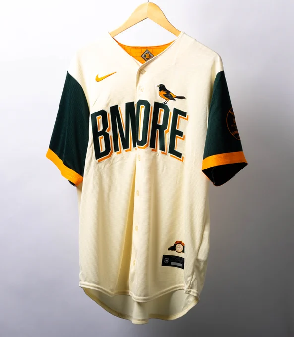 A cream-colored Baltimore Orioles City Connect jersey with green and orange lettering.