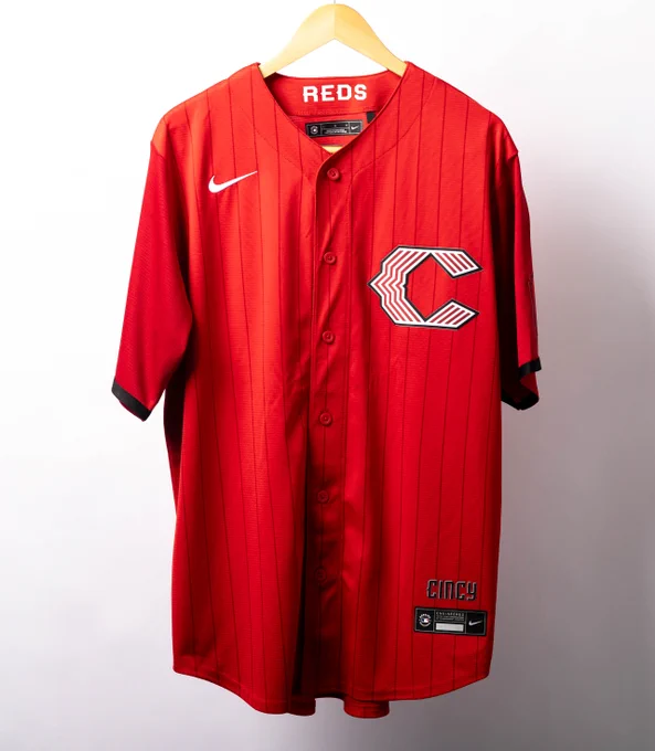 A red with black pinstripes Cincinnati Reds City Connect jersey with white, red and black lettering. 
