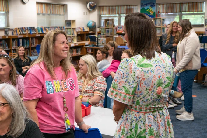 A staff member talking to the new principal of Hunt Meadows Elementary in the library