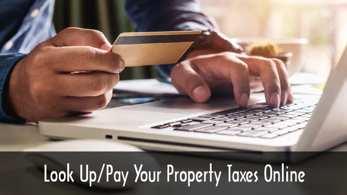 Person holding a credit card and typing on a laptop to look up and pay property taxes online.