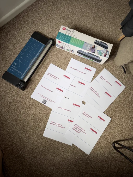 A series of papers laid out on the floor, next to a lamination machine and a guillotine