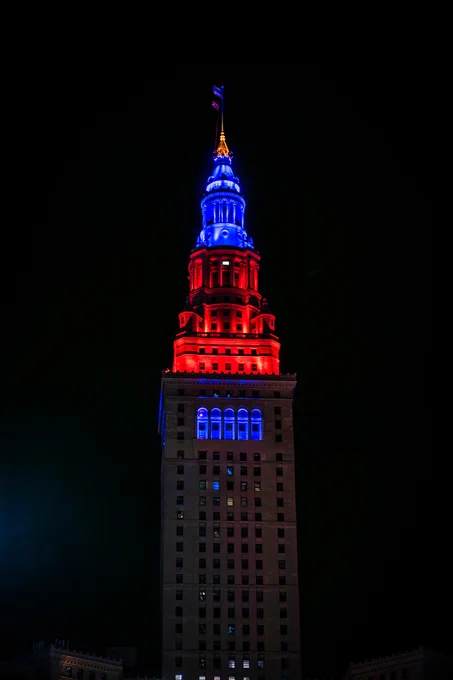 The top of Cleveland's Terminal Tower is illuminated blue and orange. The sky is dark above the building. Credit: NASA/Jef Janis