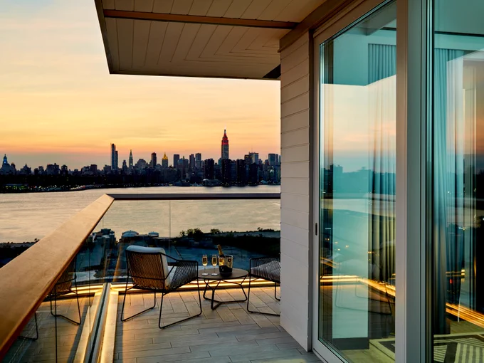 Sun sets behind Manhattan skyline as seen from private wraparound balcony at The William Vale in Brooklyn. 