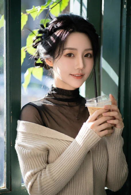 A hyper-realistic portrait in the style of a high-end CCD film aesthetic. A beautiful Chinese woman with a soft oval face and radiant pale skin, leaning against a dark green wooden window frame of a vintage cafe. She is wearing a beige ribbed-knit buttoned cardigan layered over a black sheer body mesh long-sleeve bodysuit with a high mesh turtleneck collar. The cardigan is stylishly shrugged off one shoulder to reveal her collarbone and the mesh texture underneath. She holds a plastic cup of iced coffee with a dome lid and black straw in both hands. Soft, dappled sunlight filters through overhead foliage, creating organic shadows and glowing rim light on her dark hair. Natural, relaxed expression with a subtle, charming smile. Shallow depth of field with a creamy bokeh background of green leaves. 8k resolution, cinematic lighting, extreme fabric textures, masterpiece quality, side view, zoom in to focus on her upper body much above her waist only. --ar 2:3