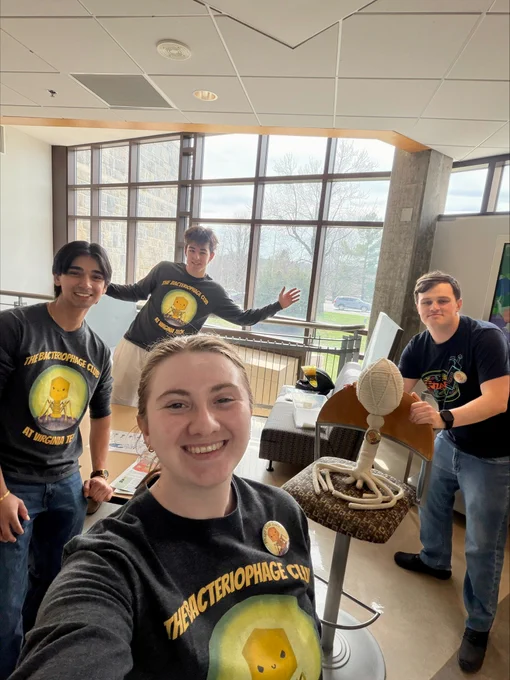 The Scharf Lab's Bacteriophage Club at Kids' Tech University. Left: Sharat Paka. Back: Eli Konvalinka. Front: Idella Collett. Right: Jackson Wood.  Jackson is next to the bacteriophage mascot, created by undergraduate student Taylor Kramp.