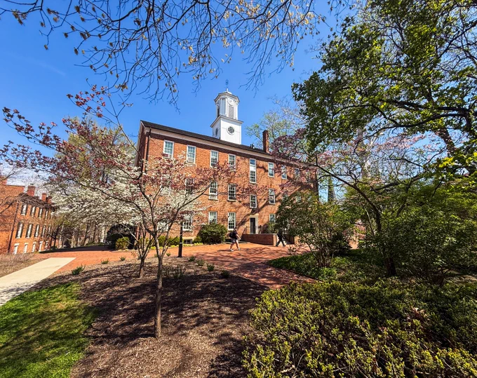 Cutler Hall on Ohio University's Athens campus surrounded by spring flowering trees and a blue sky.