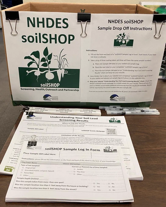 Cardboard box sitting on a table in the N H D E S lobby. Sheets of paper clipped to and sitting in front of the box read "Soil Shop sample drop off instructions," "Soil shop sample log in form," and "understanding your soil lead screening results."