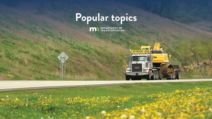 A truck is transporting large construction equipment on a highway. The scene is set with green grass and dandelions in the foreground. The text "Popular topics" and the logo for the Minnesota Department of Transportation are displayed at the top of the image.