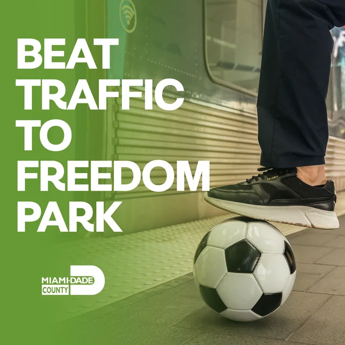 A foot wearing an \"ARIGATO\" branded shoe is placed on a soccer ball with \"BEAT TRAFFIC TO FREEDOM PARK\" and the Miami-Dade County logo. The image encourages using public transport.