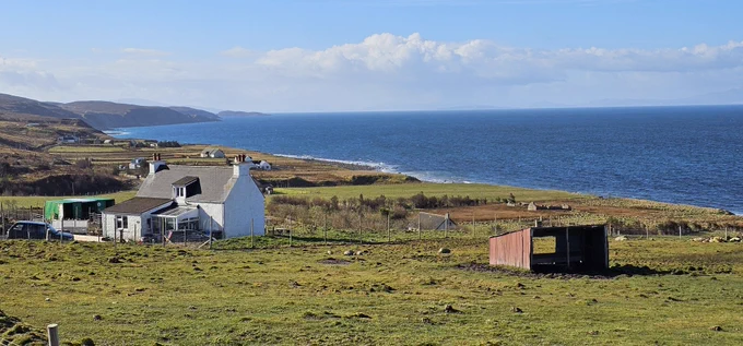 Farm houses along the western coast of Scotland sticking out in the bright green grass.