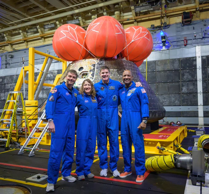 "NASA astronauts Reid Wiseman, commander; left, Christina Koch, mission specialist; CSA astronaut Jeremy Hansen, mission specialist; and NASA astronaut Victor Glover, Artemis II pilot, right, pose for a group photo after viewing the Orion spacecraft in the well deck of USS John P. Murtha on Saturday, April 11, 2026. Photo Credit: NASA/Bill Ingalls"