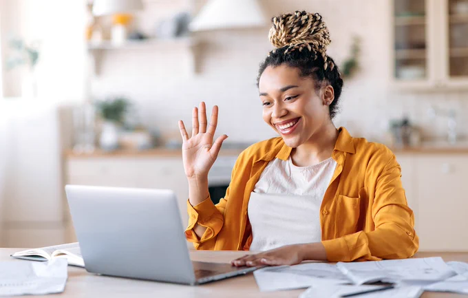 Young woman waving at a laptop